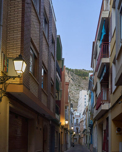 Streets of Cullera. A picturesque street scene with tall buildings and a distant hill.