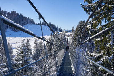 Sattel, Swiss Alps. A serene river is adorned by a beautiful bridge, where people stroll leisurely.