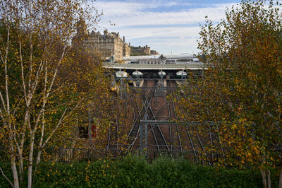 Autumn light over Edinburgh's riverfront frames a quiet city scene with iron viaducts and gold-leaved trees.