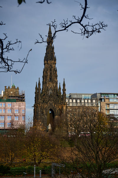 Gothic spire of Scott Monument rises over Edinburgh's skyline amid bare trees and autumn light.