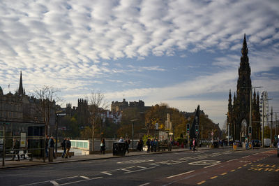 Edinburgh's historic skyline glows as Scott Monument towers beside a lively street, with Edinburgh Castle punctuating the distance.