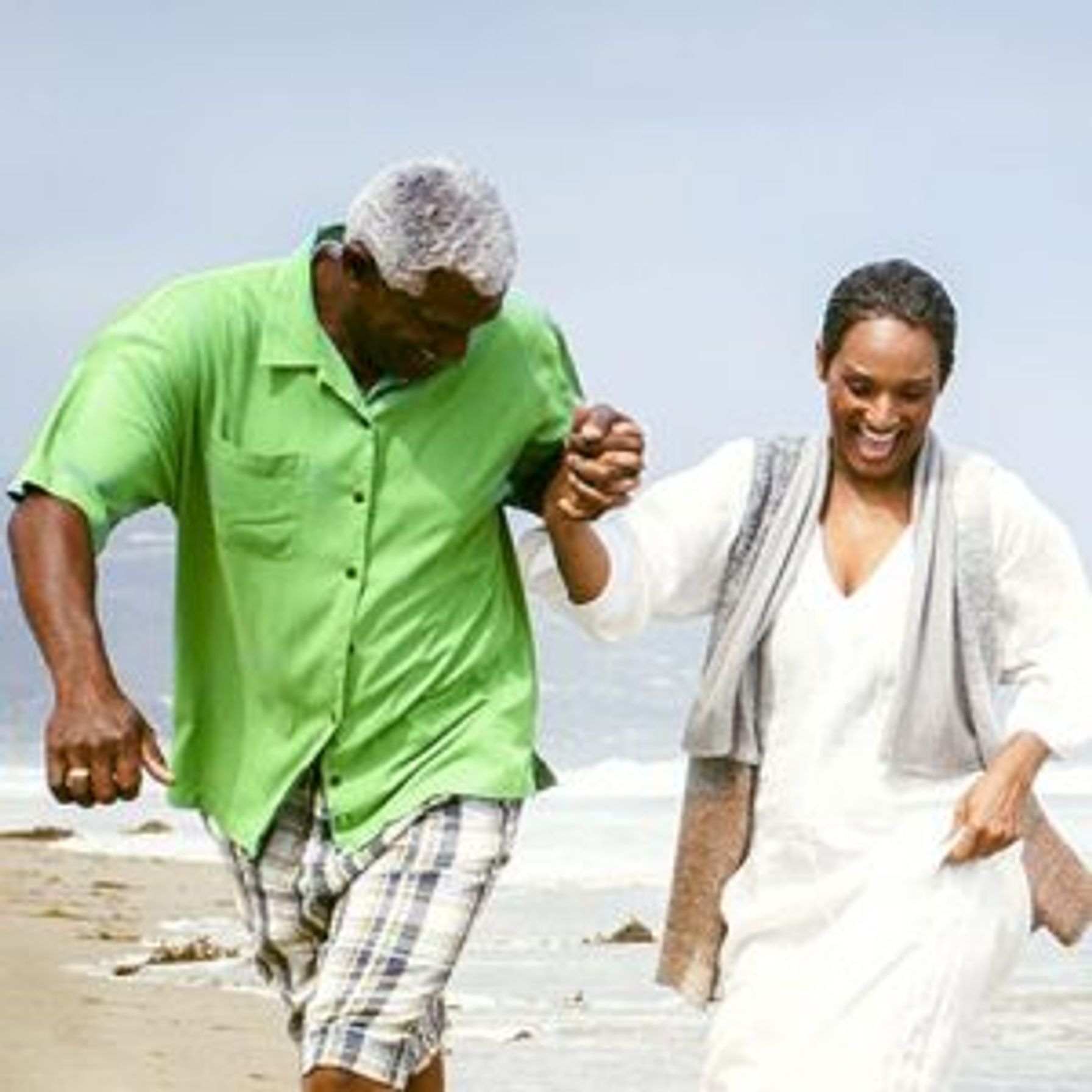 A middle-aged couple holding hands and walking on the beach