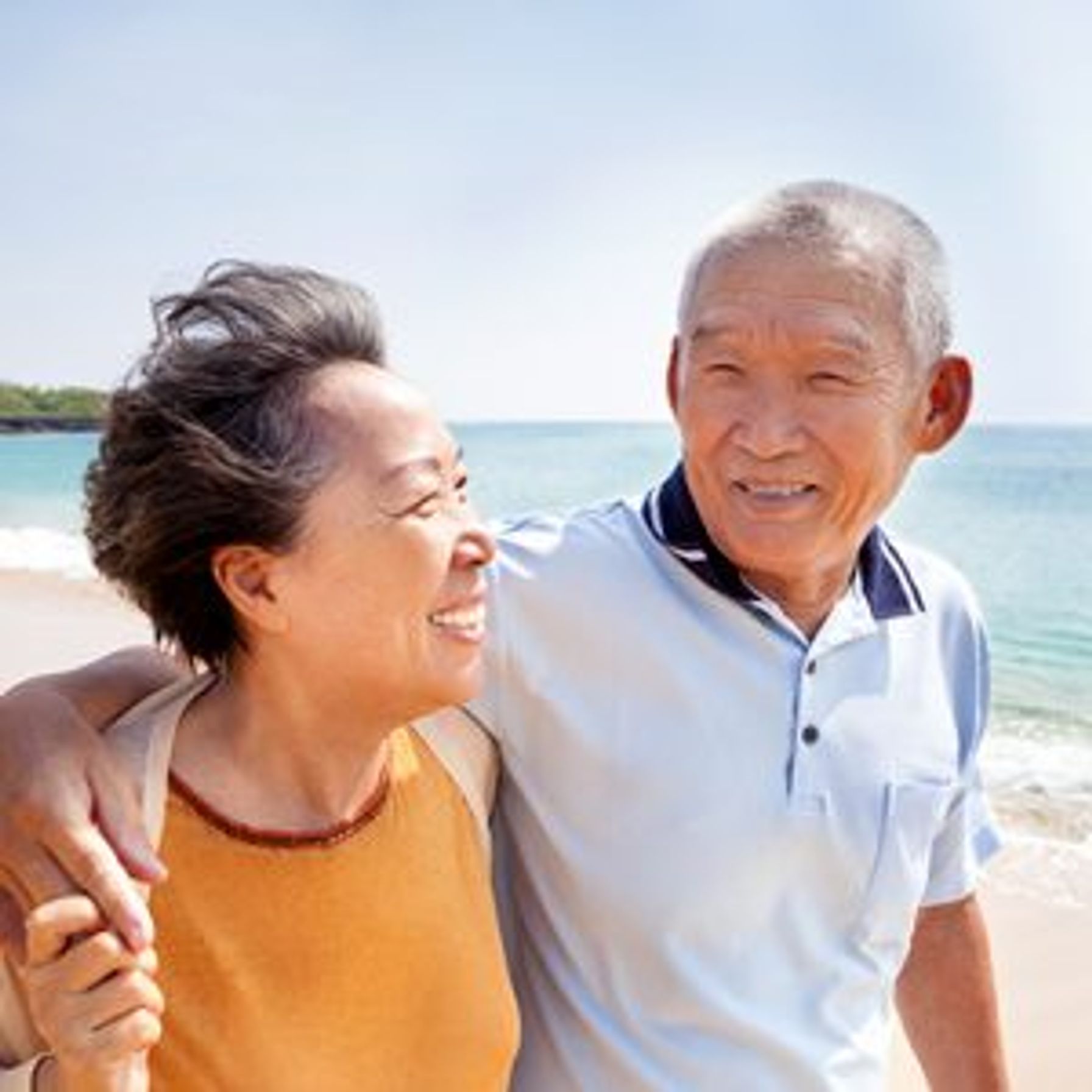 Eldery Asian couple walking on the beach