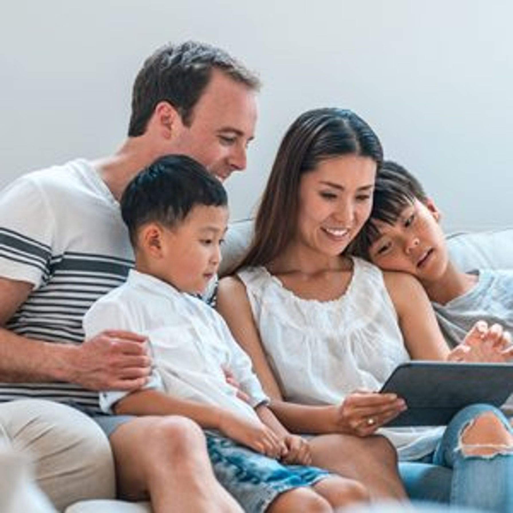 A family of four sitting on couch with Ipad