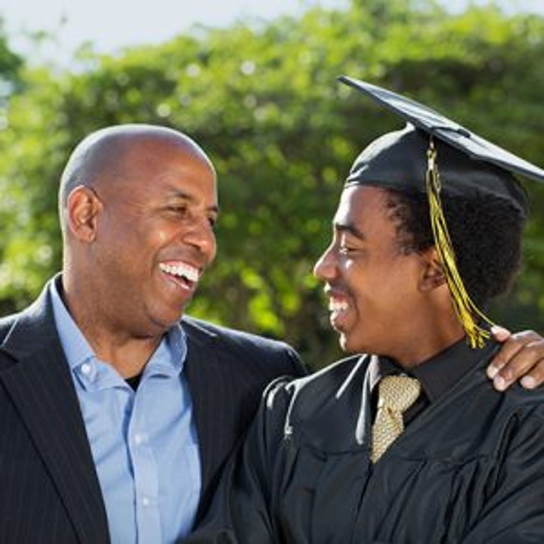 Dad smiling at his son in a graduation gown