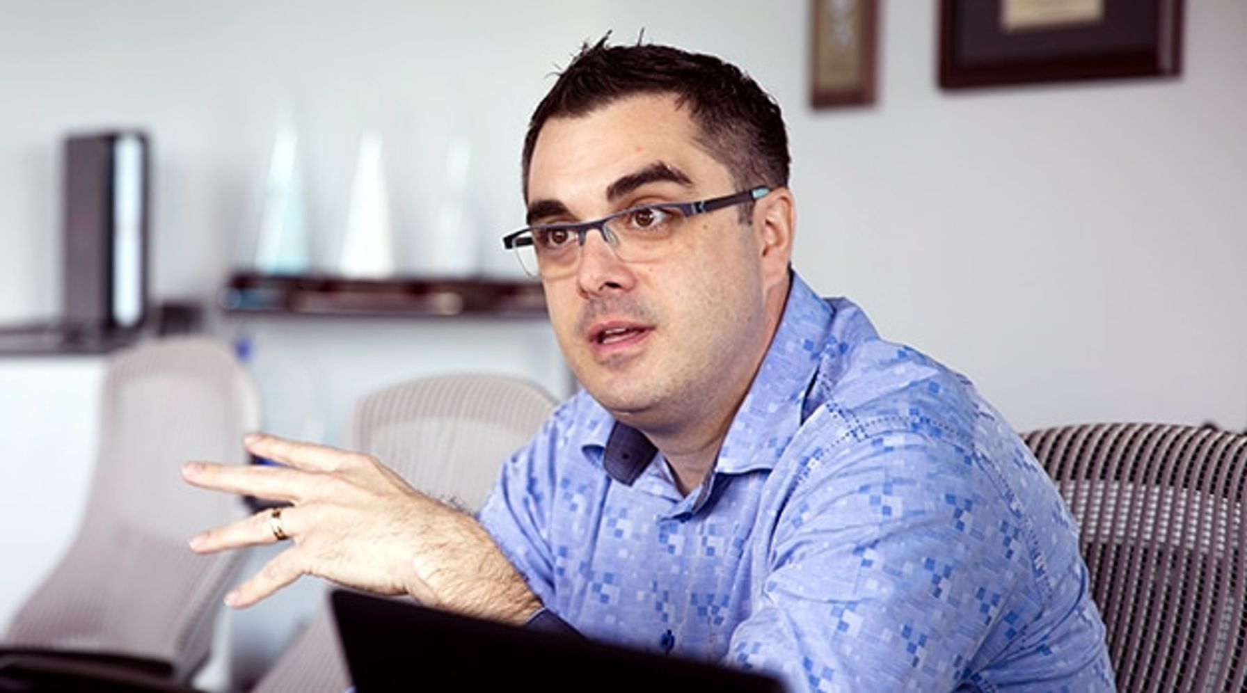 A man with glasses sitting down, talking