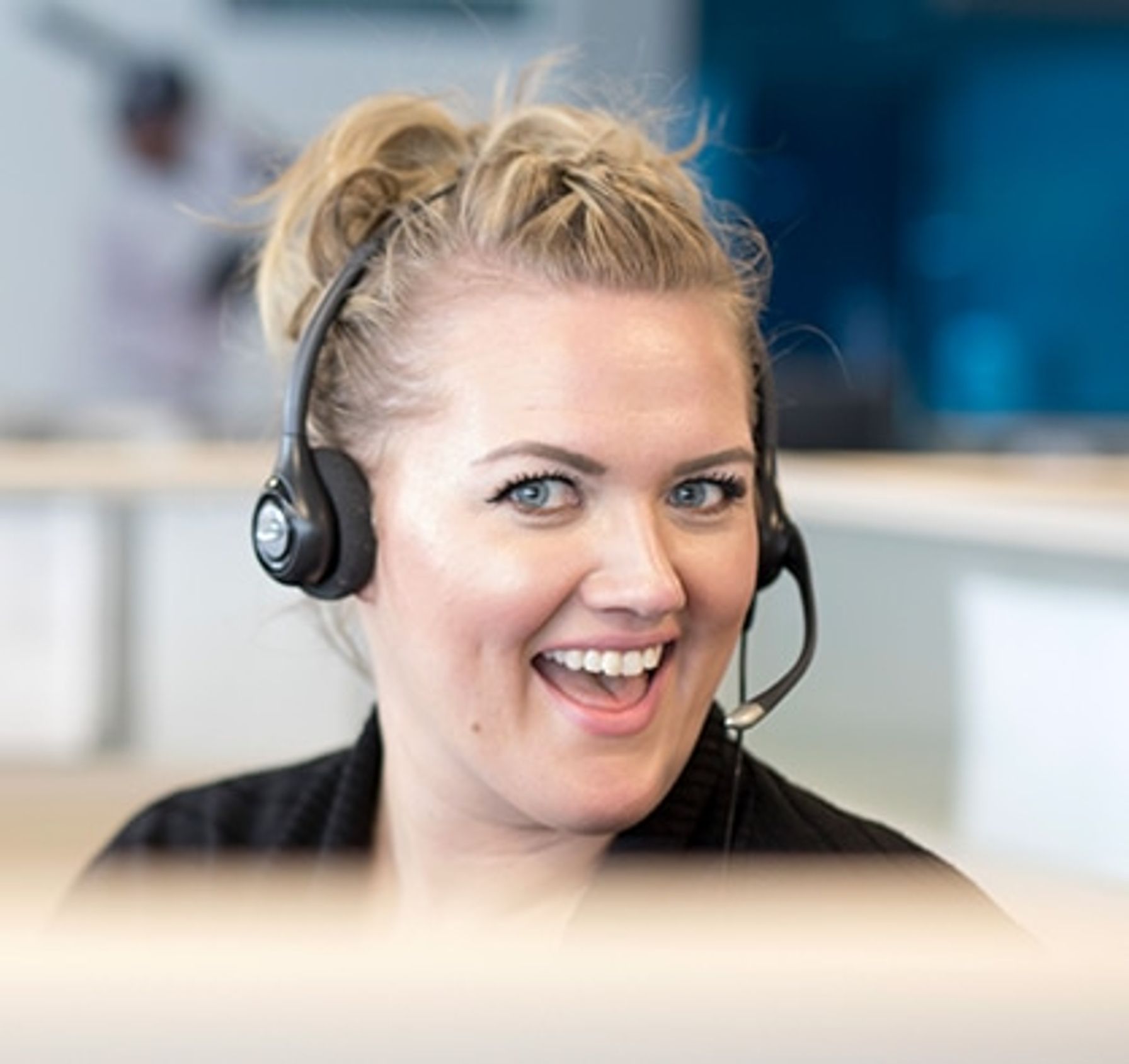 Blonde woman with a headset smiling at work