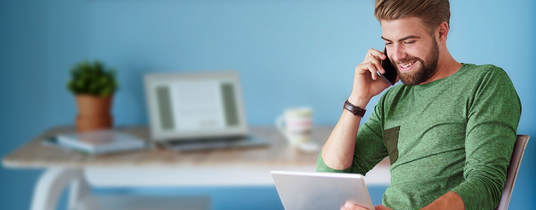 Man sitting with a laptop, talking on the phone