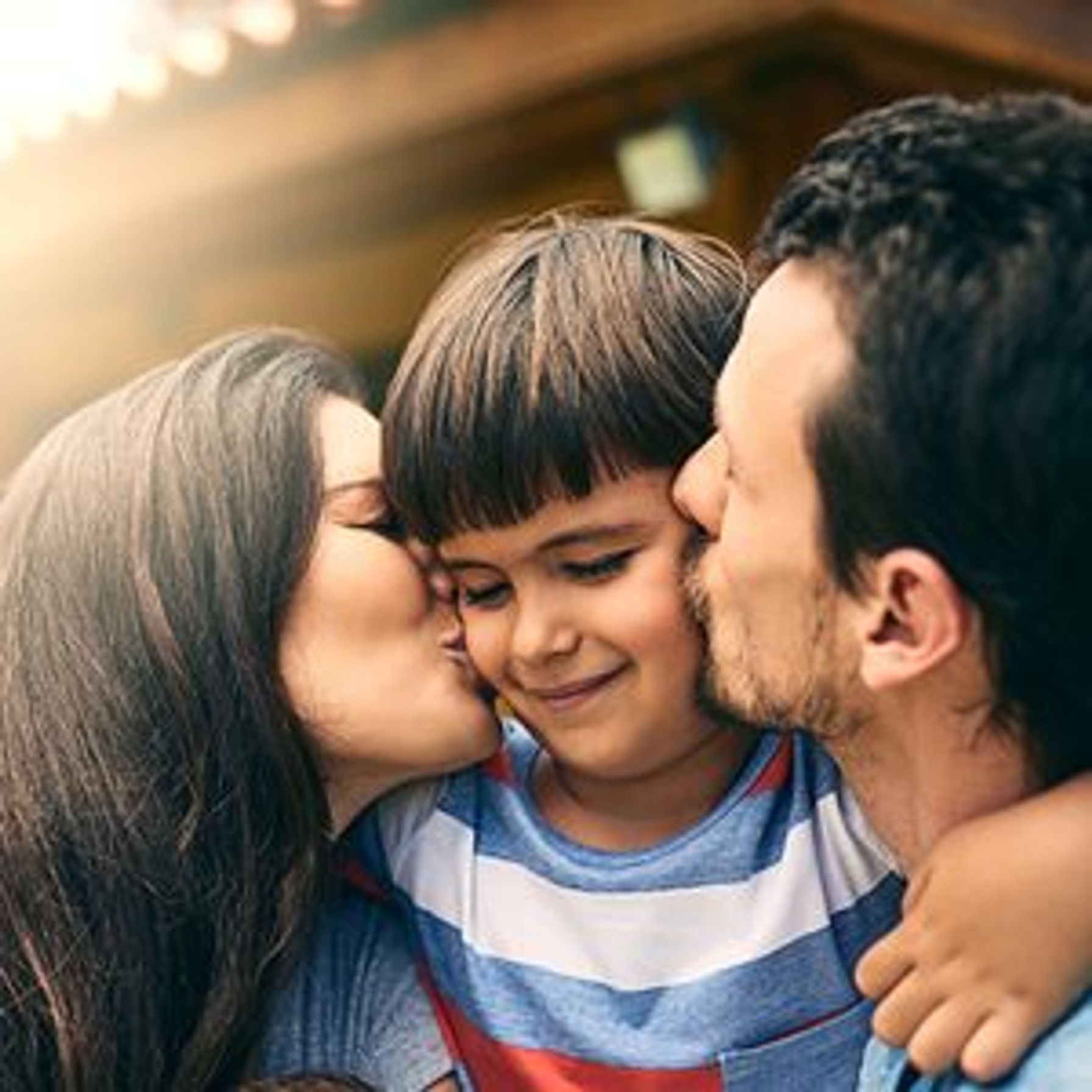 Two parents kissing their son