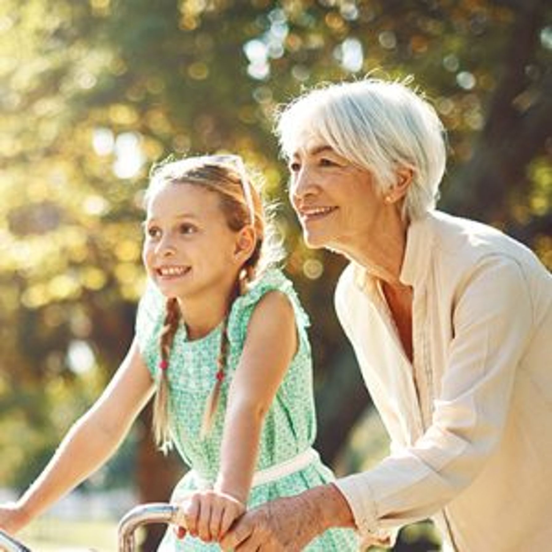 Elderly woman helping a girl ride a bike