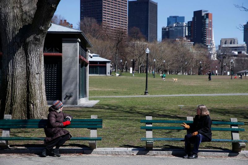 Social distancing photos - two women talking sitting in separate benches at the park