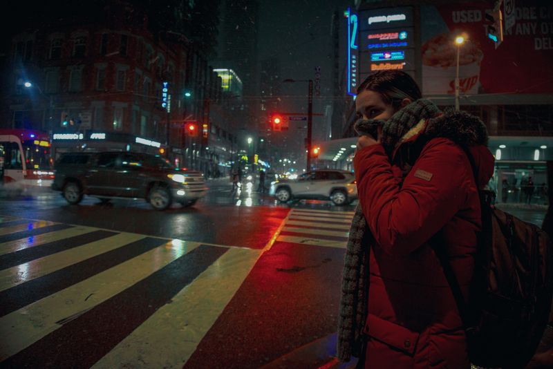 Coronavirus and Taxis - girl covering her mouth with a scarf walking in the city at night
