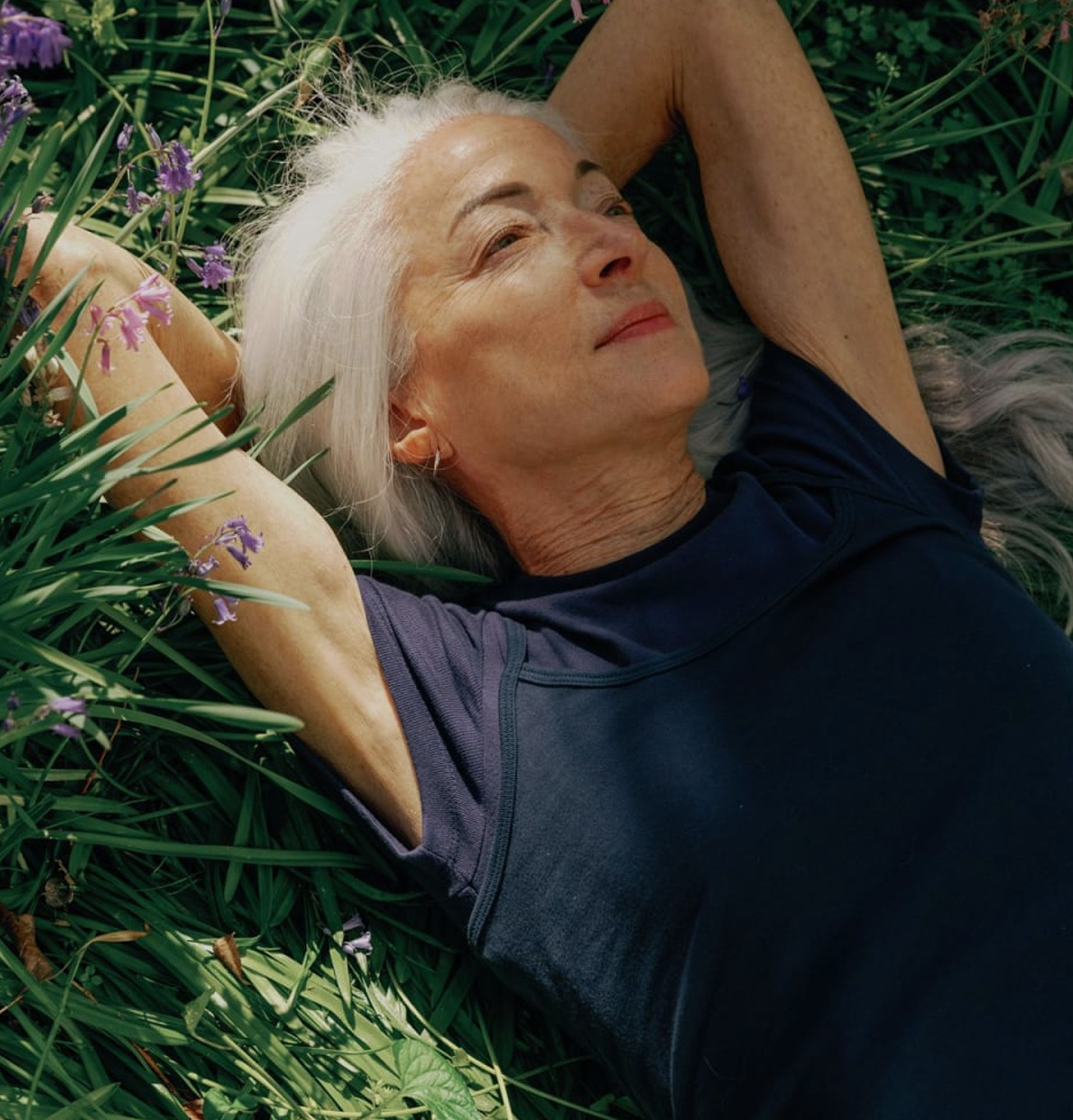 Lady lying amongst flowers with arms behind her head