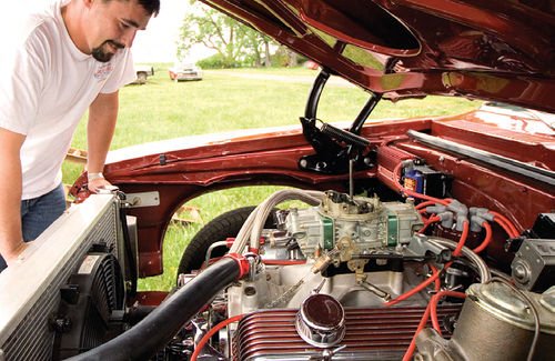 Mike pauses for a fond look at his Chevy’s 406 V-8. Some carb work has cut his quarter-mile times.