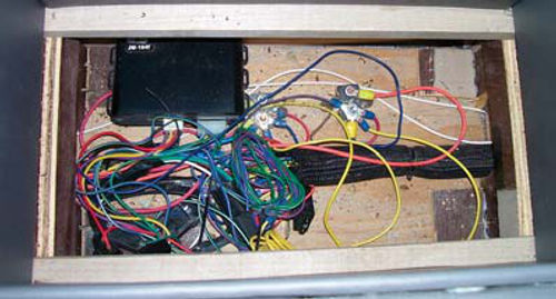 Photo 7. With the false bottom removed and looking down through the storage compartment, the wires, circuit breakers, and transmitters for the remote door latches are visible.