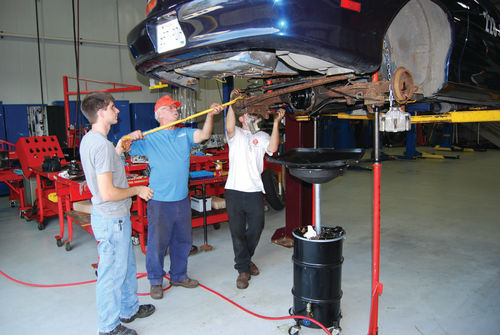 One of the adult advisors helps two students chain the Camaro’s rear suspension to make the car sit lower and be more aerodynamic. Wheel wells had to be enlarged with snippers to accommodate borrowed racing wheels and tires.