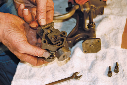 8. Vince’s right hand supports the governor plunger stop. His left hand is by the plunger and bushing assembly. The round part near the camera is the governor valve body.