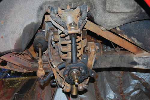 A vertical link holds the A-arms together on the outside with a ball joint at the top and trunnion at the bottom. The shock runs up through the coil spring and also secures the A-arms.