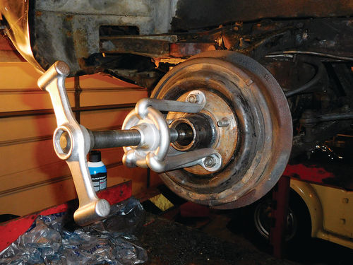 To remove the brake drum, use this style puller that bolts to three wheel studs using the lug nuts. A notch in the round disc allows the three legs to be slid onto the disc. The spinner handle goes on the center bolt to turn it against the spindle.