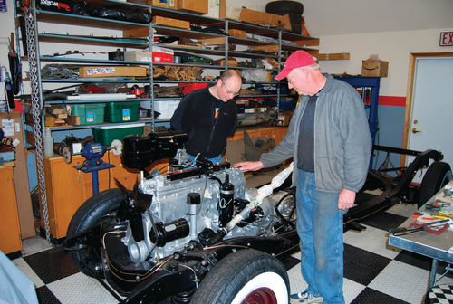 Bob Hansen of Gunner’s Great Garage (with the red hat) shows Josef Hladik details of the ’48 Chrysler chassis and power train that he has been putting together.