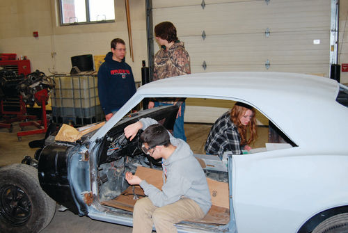 Isiah Wentzel adjusts the steering wheel while other students keep busy with other tasks. There’s more to do on the Camaro than was first anticipated.