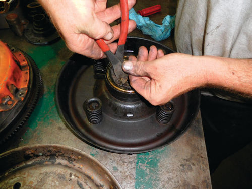 Special pliers are used to remove the springs or clips that hold the throw-out bearing to the original clutch that lost its leather lining.