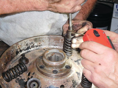 Ron Paige used a brake hold down spring tool to re-install the keepers on the springs once the parts were transferred to the good used clutch. A helper holding the orange flashlight used a small screwdriver to position things.