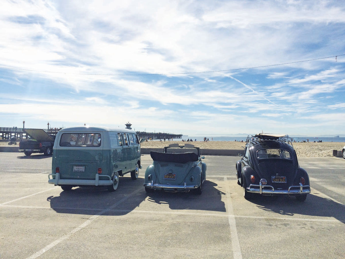 the three Volkswagens appear to be looking out towards the ocean.