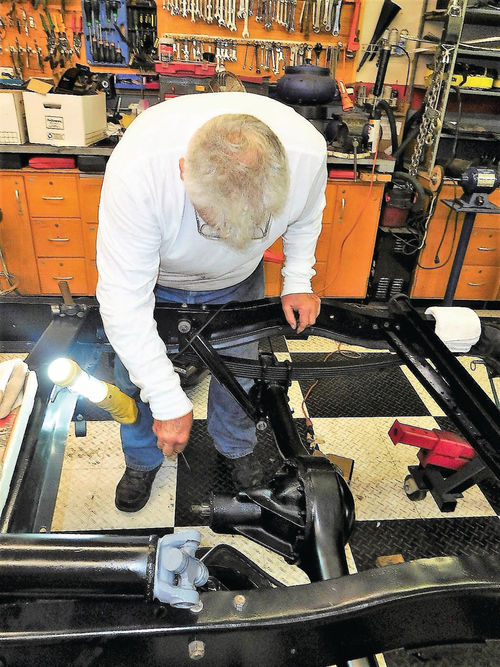 Larry Obiala uses a small screwdriver to clear grease off the differential seal so the seal number could be read using a flashlight.