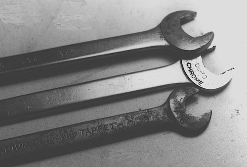 Tappet wrenches make the job easy, but are hard to find. You can grind ordinary open-end wrenches thinner and they will work just as well.