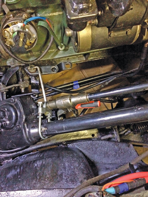 An under-hood view showing the relocated shifter shaft—held by a new U-bracket—and revised operating linkage.