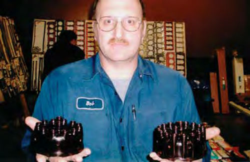 Bob Marx holds a distributor cap for a Nash Twin-Ignition Six in his right hand and another for a Nash Twin-Ignition Eight in his left hand.