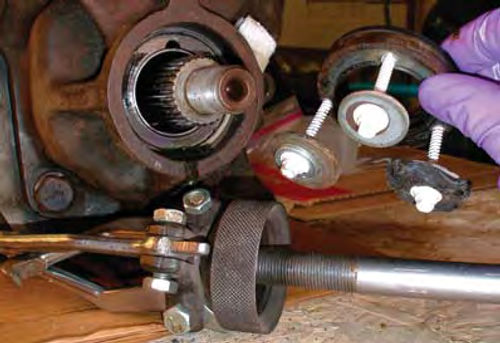 Photo 14: By working the slide hammer (foreground) around the three screws I placed in the old oil seal, it popped out with no damage to the transmission shaft.