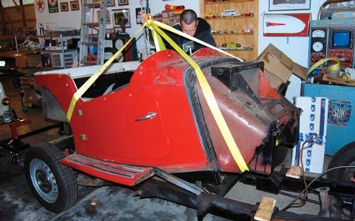 A chain hoist and towing straps were used to lift the body tub from the frame. The body is sheet metal over a wood-framed structure. The car frame is steel.