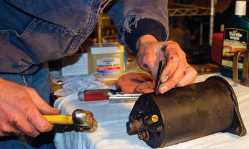 Vince Sauberlich stamps the end plates and housing of the yellow MG TF’s generator so that everything can be put back together in the same position.