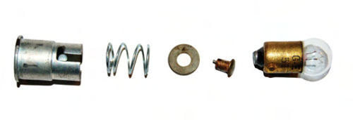 From left, bulb holder, short spring, fiber washer and brass button carry power to bulb (right). A piece of broken wire protrudes from the “neck” of the brass button.
