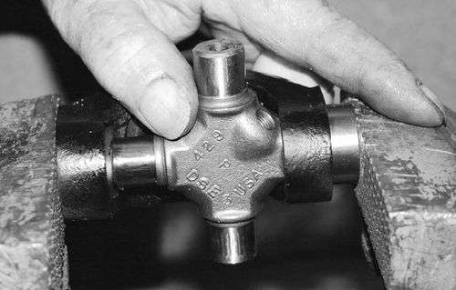 Insert the cross to keep the needle bearings straight. Gently press in each bearing cap until flush using the vise.