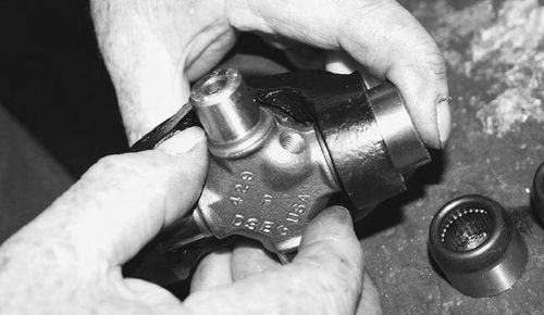 Make sure the grease fitting opening is facing correctly, then insert a bearing cap and yoke.