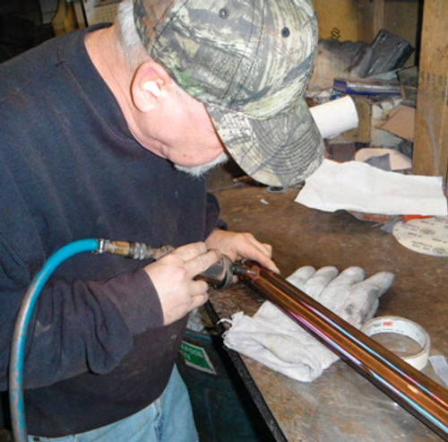 An employee at Paul’s Chrome Plating performs detail grinding on pits, preparing the part for solder.