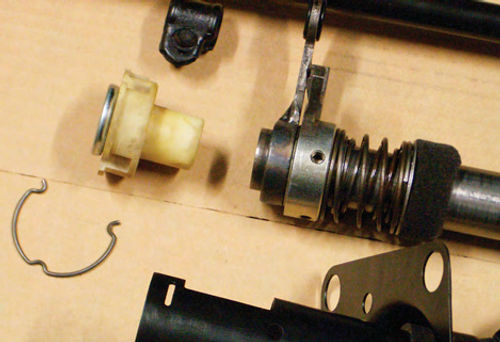 A close-up of the lower shift tube assembly. At left center is the lower column bearing and its retainer/adaptor, the retainer clip, and at the bottom is the mast tube and cover plate.