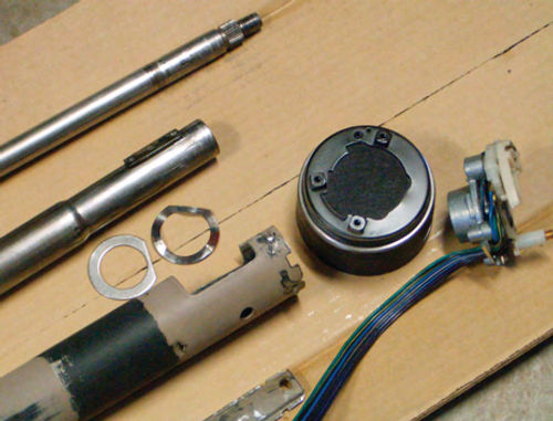 Top to bottom: the steering shaft, the shifter tube, two special washers, the mast tube (main housing). At the right is the shifter housing and the upper bearing assembly with turn signal switch. At the bottom is the wire cover.