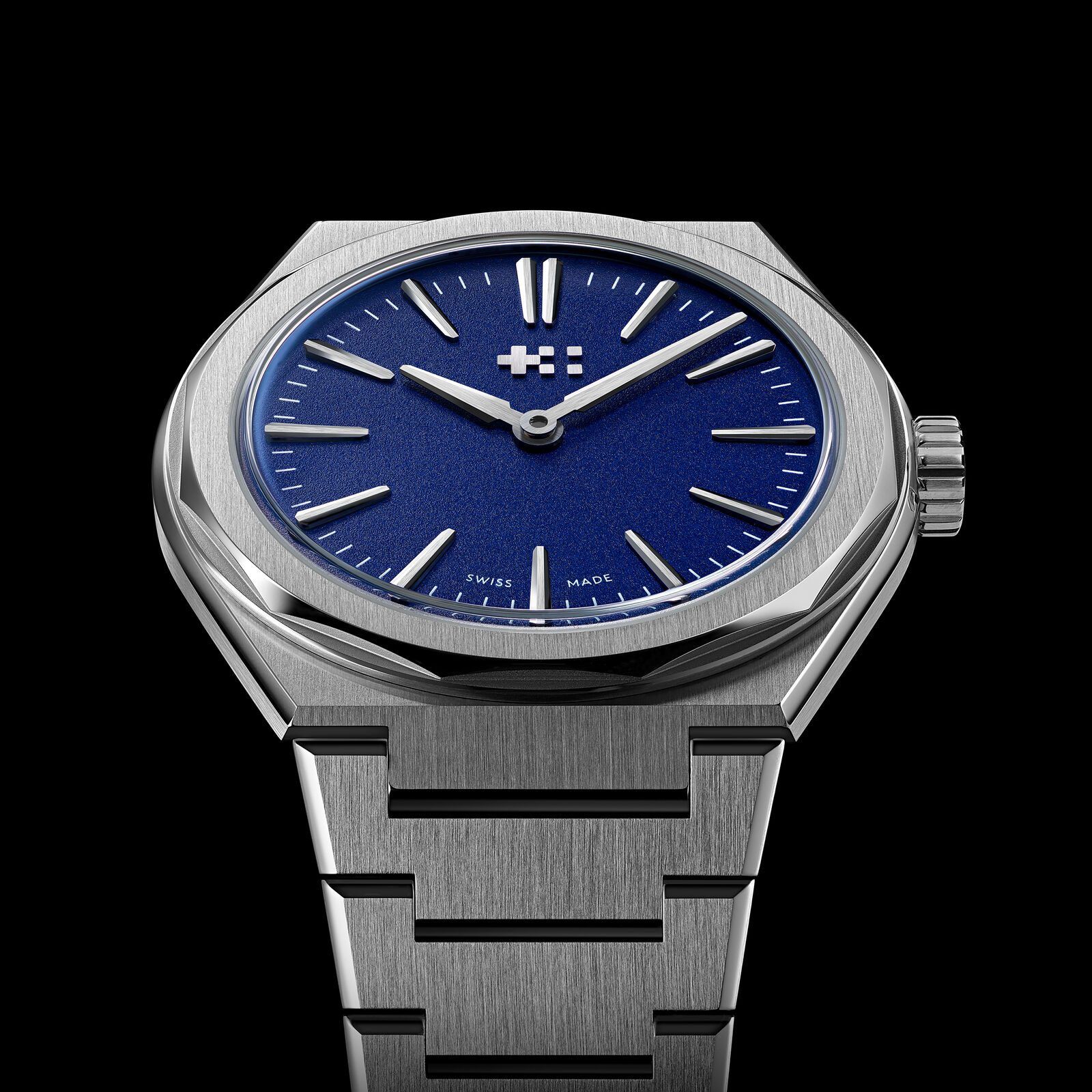 The blue Twelve 660 from the front against a black background, with light catching the polished bezel facets and the brushed centre links of the bracelet