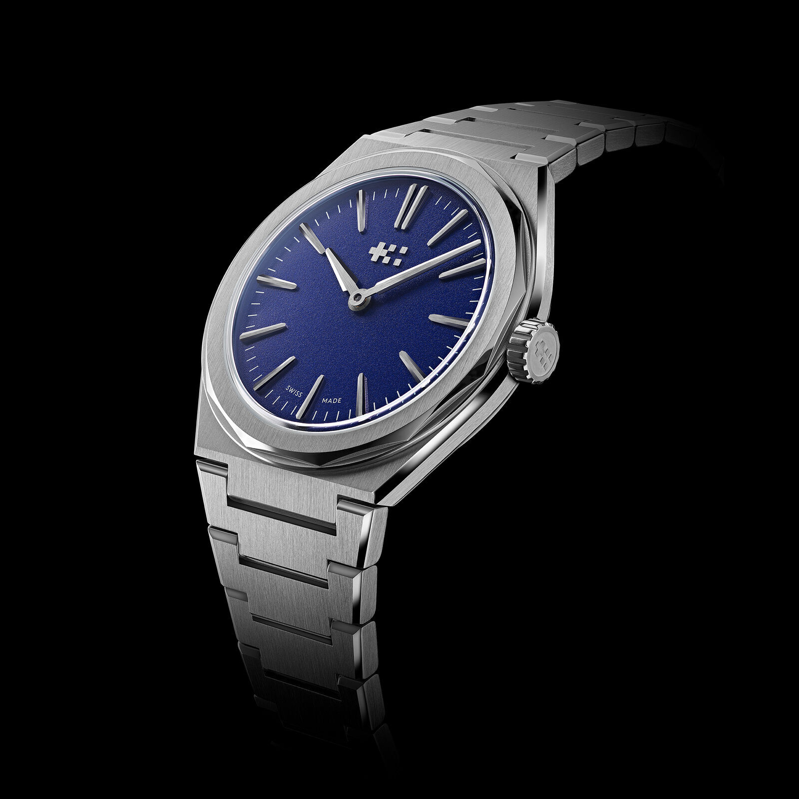 Three-quarter view of the blue Twelve 660 on its bracelet against a black background, showing the 12-sided case, the push-in crown at 3 and the tapering links