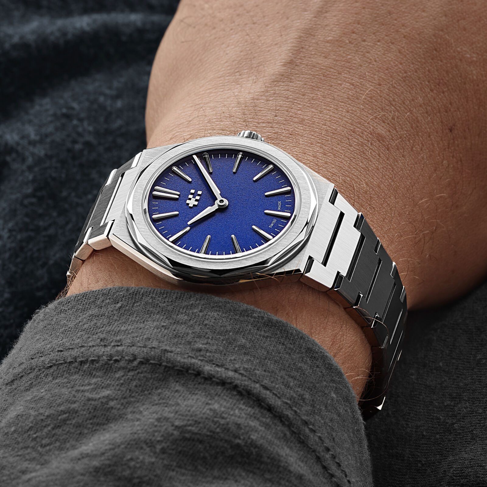 The blue Twelve 660 on a wrist, worn with a dark grey sweater cuff, showing how flat the case and bracelet sit