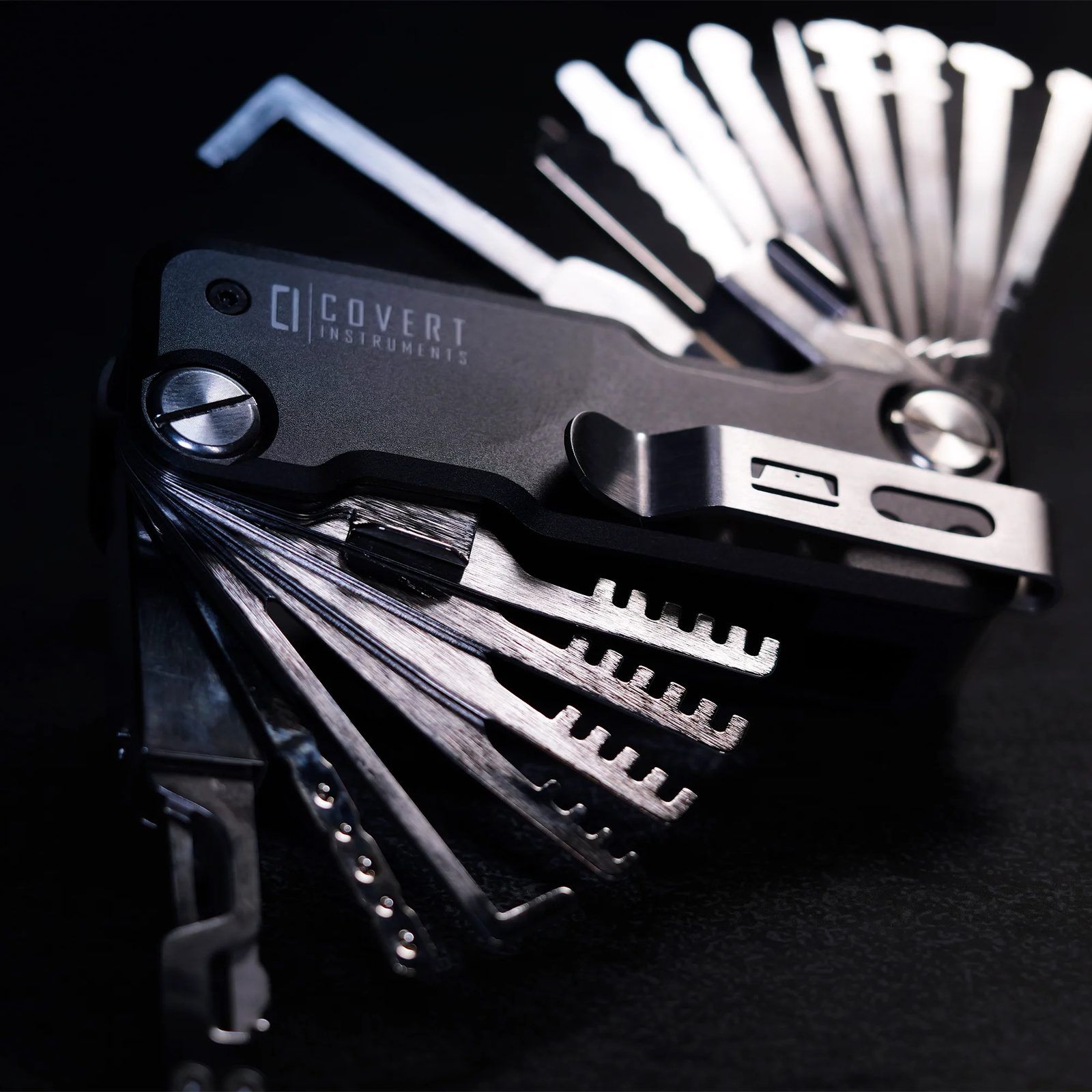 Covert Companion Pro on a black surface with its picks, combs and turning tools fanned out from both ends of the black anodised body