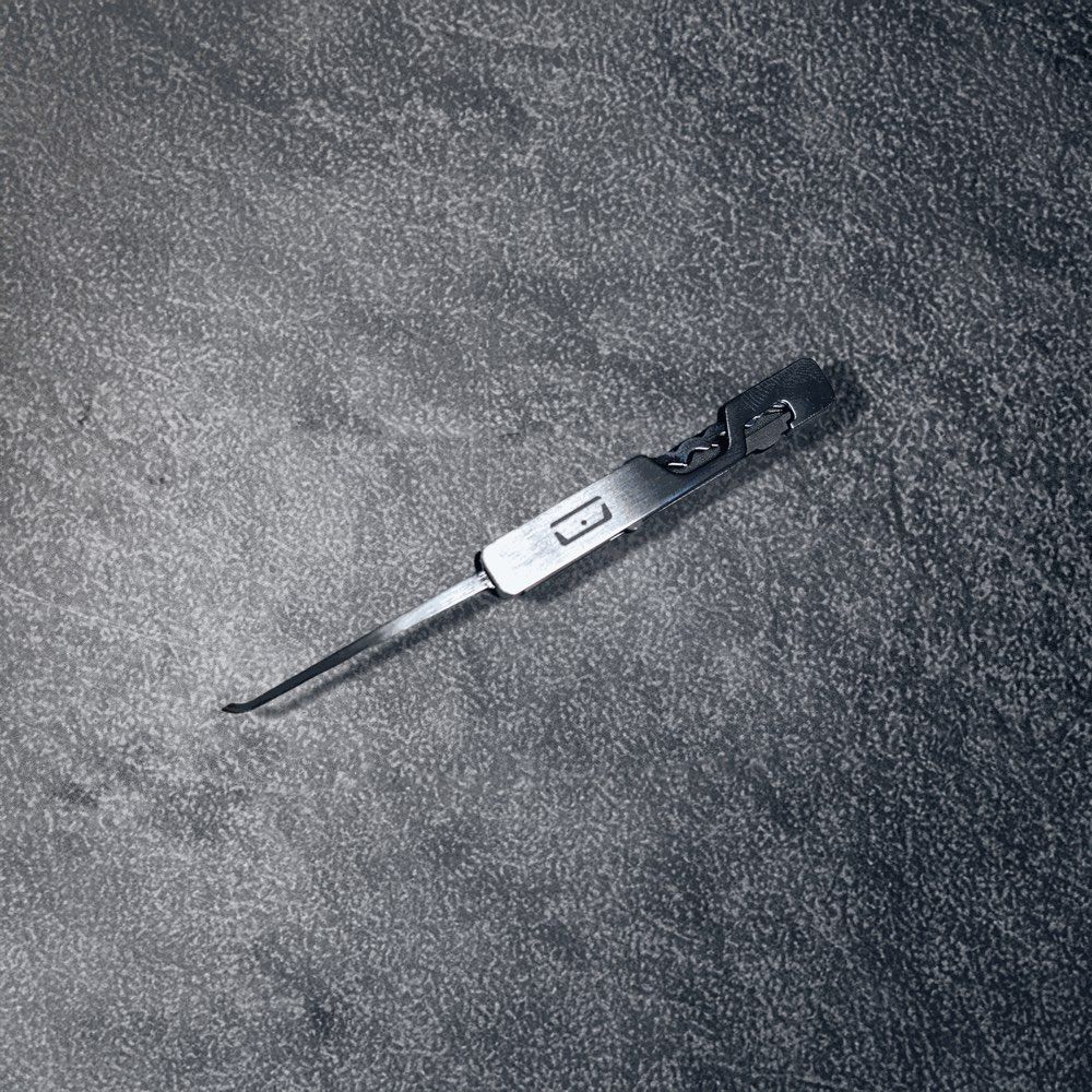 Close-up of the folding utility pick deployed on its stainless steel carrier, showing the hook profile extended straight out from the handle