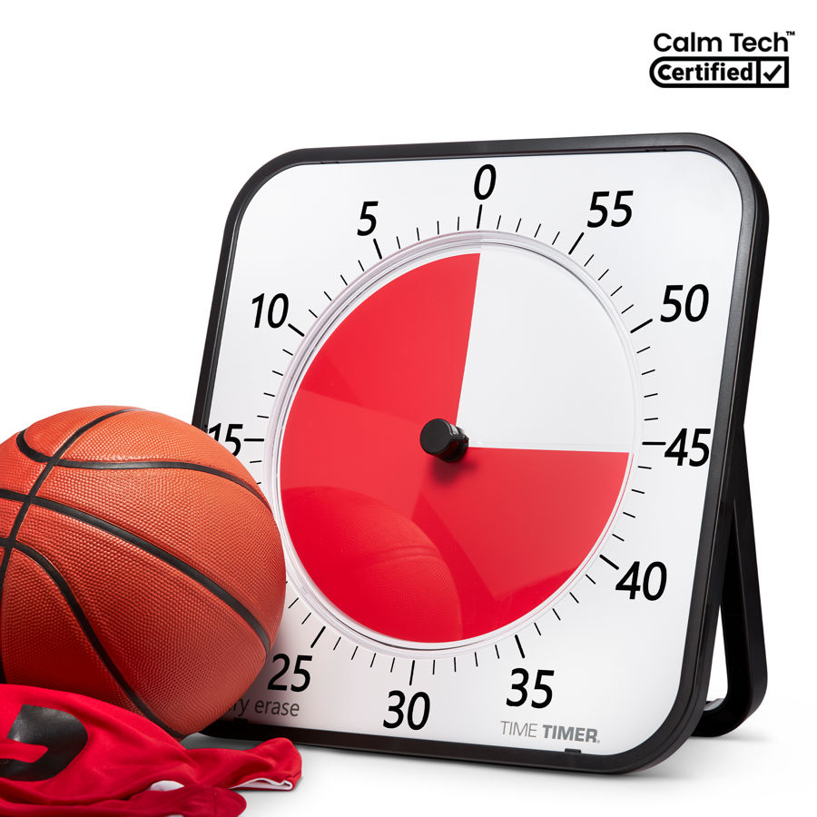 Time Timer MAX on its kickstand next to a basketball, a large black-framed square timer with a red disk covering about three quarters of the dial