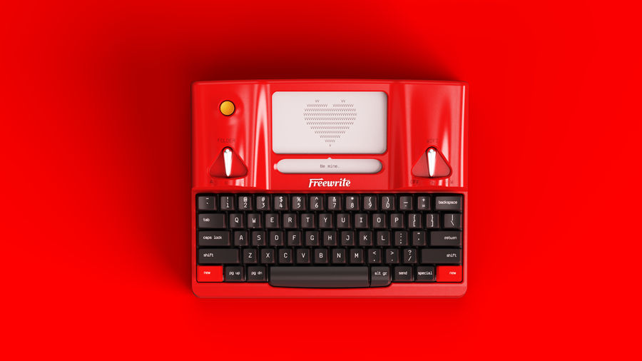 Smart Typewriter Valentine Special Edition in glossy red with black keycaps, shot against a matching red background, its screen reading Be mine