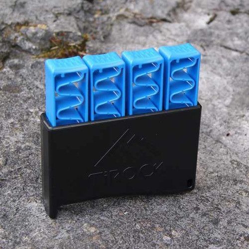TiROCK Ti-Hand finger trainer, four blue spring-loaded finger pads on a black base, photographed on rock