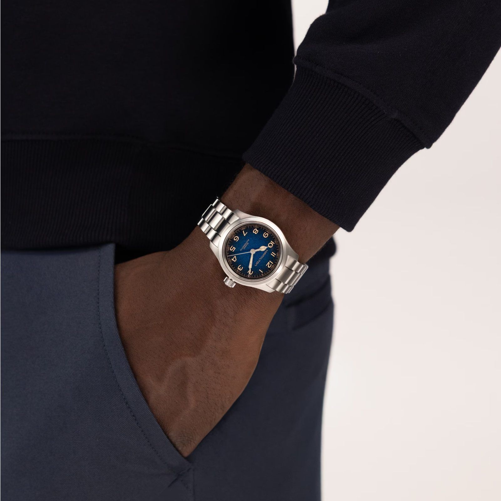 The blue Murph worn on the wrist under a navy sweatshirt cuff, the dial reading dark against the steel bracelet